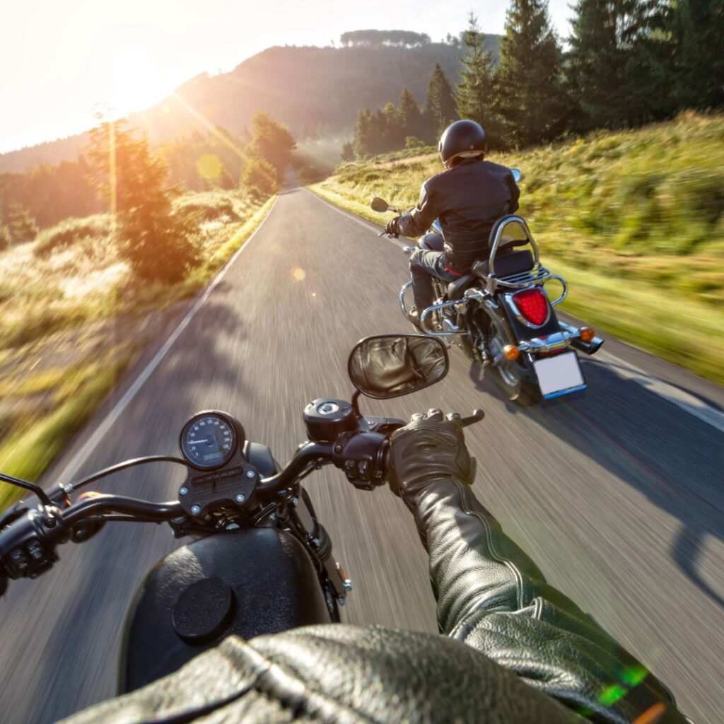 Two motorcycles driving down the road.